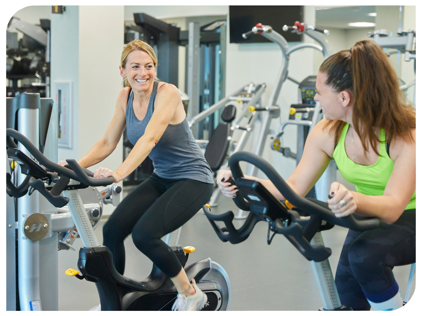 Two employee exercise on stationary bikes.